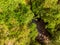 Aerial drop down view of forest waterfall falling into pond.