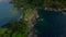 Aerial dynamic dive view to rocky beach mountain covered green plants ocean