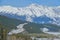 AERIAL: Empty mountain road winds across a pine forest below Canadian Rockies.