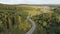 Aerial of the empty road going through forest, summer nature landscape. Scene. Flying above the highway through the