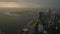 Aerial evening shot of modern urban district at sea coast. Large city after sunset. Illuminated cranes in seaport in