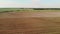 Aerial: farmer on a tractor plows the land before sowing with a modern revolving plow