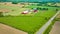 Aerial farmland with cows grazing in green pastures and distant red barn and stable