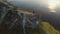 Aerial flight above couple in love standing in cliff edge near water. Woman in amazing red dress. Man in black. Sunset.