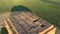 Aerial flight above large hay stack in spring field, afternoon sunshine