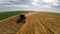 Aerial flight over combine harvesting the wheat rows