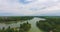 Aerial flight over river with fishermen sitting in boats and forest belt along r