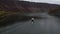 Aerial fly over river in canyon. Boat sailing on a wide river, rear view from above.