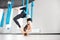Aerial fly yoga in white gym, young gymnastics women in blue hammock