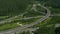 AERIAL: Flying above a modern network of highways running through green nature.