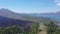 AERIAL: Flying above rough stony black lava terrain and grey ashy volcanic soil at the toot of Mount Batur towards the