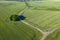 Aerial flying above stunning green wheat field swaying in the wind, forests, river, roads and water channel on country farmland