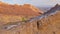 AERIAL: Flying behind a female photographer trekking along a sandstone formation