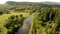 Aerial flying of drone over mountain river, field, forest and path.