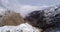 Aerial flying moving forward over snowy mountain ridge valley with clouds and sun establisher. Outdoor snow alpine wild