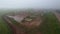 Aerial flying on oil pumps at oilfield cluster in a foggy field after rain. Muddy ground puddles hard working conditions