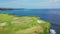 AERIAL: Flying over beautiful golf course on overgrown rocky cliff top in sunny luxury tourist resort on paradise island
