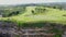 AERIAL: Flying over beautiful golf course on overgrown rocky cliff top in sunny luxury tourist resort on paradise island