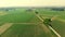 Aerial: flying over cycle lane crossing countryside, people cycling along bikeway through cultivated fields and farmland, sprintim