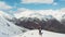 Aerial: flying over hiker on snowy mountain top, ski touring mountaineering snow mountain, panoramic view on the alps, conquering