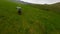 Aerial follow dynamic view enduro motorbike rider speed driving on green grass