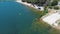 aerial footage along the sandy beach at Silverwood Lake with rippling water and lush green trees, grass and plants and people