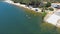 aerial footage along the sandy beach at Silverwood Lake with rippling water and lush green trees, grass and plants and people