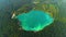 Aerial footage of azure waterscape inside artificial pit. Cherepashyntsi quarry with sandy banks and dense forest on the