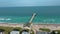 aerial footage of the blue ocean water along the coastline at Johnnie Mercer\\\'s Fishing Pier with people on the sand