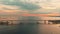 Aerial footage of cable-stayed bridge at sunset, car traffic on the highway over water, magic reflection on water, water