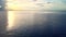 Aerial footage of the calm ocean with golden sunlight on the front