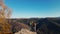 aerial footage couple hikers standing on top of cliff with raised arms. man and woman travelers enjoying great view in