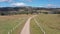 Aerial footage of a dirt road with white fence post markers in a green agricultural field