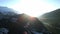 Aerial footage flight at sunrise in the mountains. The dawn rays of the sun shine from behind the mountain. Spectacular mountainou