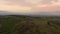 Aerial footage flying over grassy meadows, hills and farmland during sunset