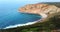 Aerial footage of a golden high cliffs of a rocky mountain blue deep water waves