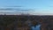 Aerial footage of a gorgeous blue lake surrounded by autumn colored trees and lush green trees and yellow winter grass