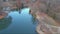 Aerial footage of a gorgeous blue lake surrounded by autumn colored trees and lush green trees and yellow winter grass