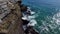 Aerial footage of the gorgeous green ocean water with waves crashing into the rocks at West Street Beach in Laguna Beach