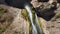 Aerial footage of a gorgeous waterfall covered with green and yellow algae surrounded by lush green trees and plants