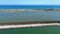 Aerial footage of a green road between body of water with blue sky on the horizon