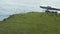 Aerial footage of a green rocky piece of land surrounded by a wavy blue sea