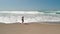 Aerial footage of a hip young woman at the beach running from the crashing waves of the Oregon coast near Lincoln City.