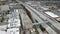 Aerial footage of a long winding freeway with cars and trucks driving on the road surrounded by vast miles of buildings