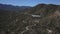 Aerial footage of a long winding highway through majestic mountain ranges covered in lush green trees and plants