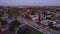 aerial footage of the Monrovia High School with a bell tower, lush green trees and grass, homes and cars on the street