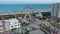 aerial footage off the Carolina Beach Boardwalk with a Ferris wheel, colorful amusement rides, people walking, a sandy beach