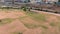 aerial footage of the people relaxing in the park with footpaths, lush green trees and grass, railroad tracks and apartments