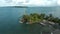 Aerial footage of a piece of land with palm trees surrounded by sea waters on a sunny day