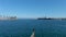 aerial footage of the rippling blue waters of Long Beach Harbor with boats sailing, the Queen Mary, lush green palm trees